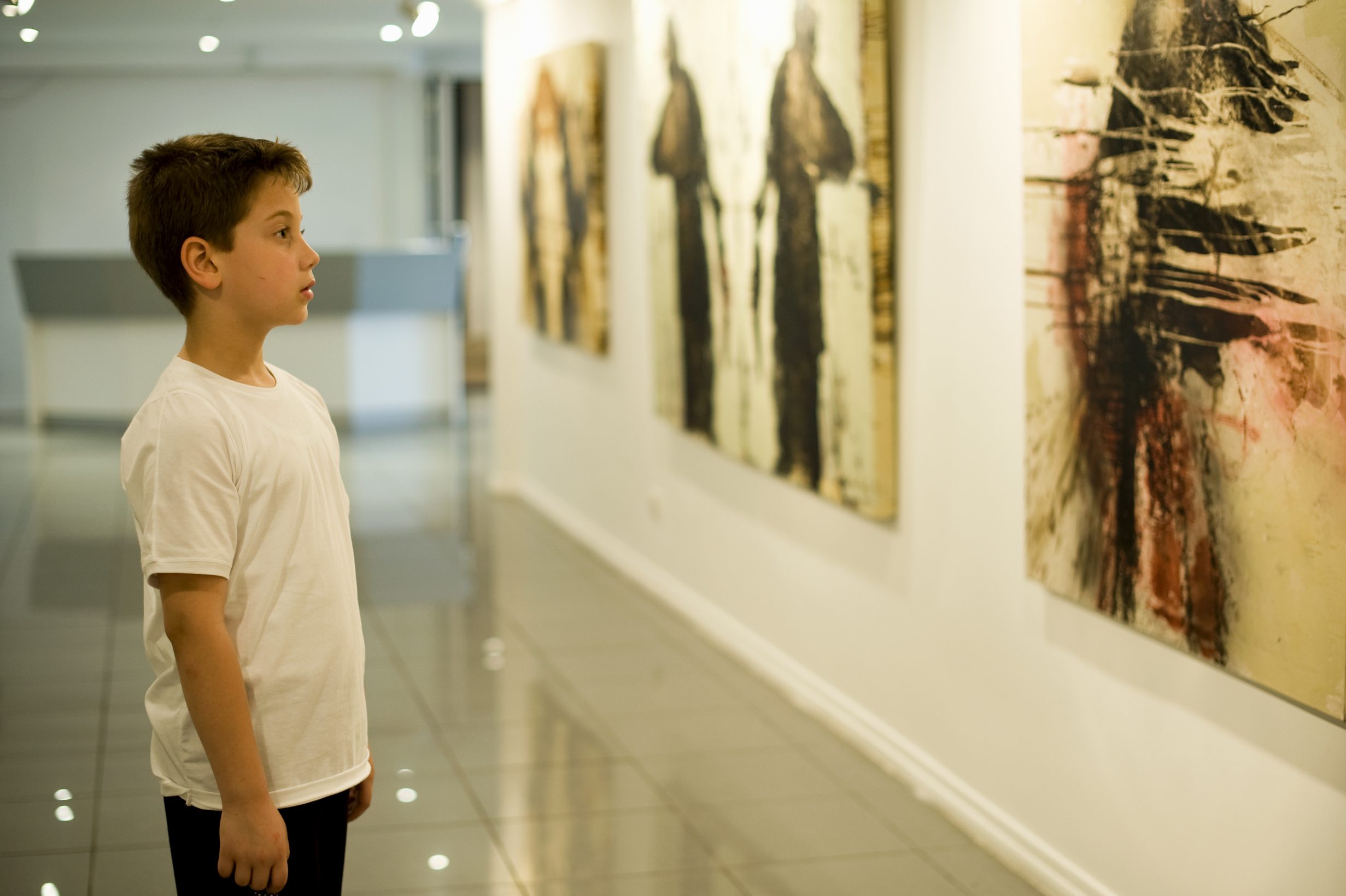 Niño contemplando un cuadro contemporáneo en la galería de arte de Tarragona EstigiArt